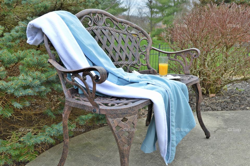 Blue bathrobe laid out on a bench outdoors
