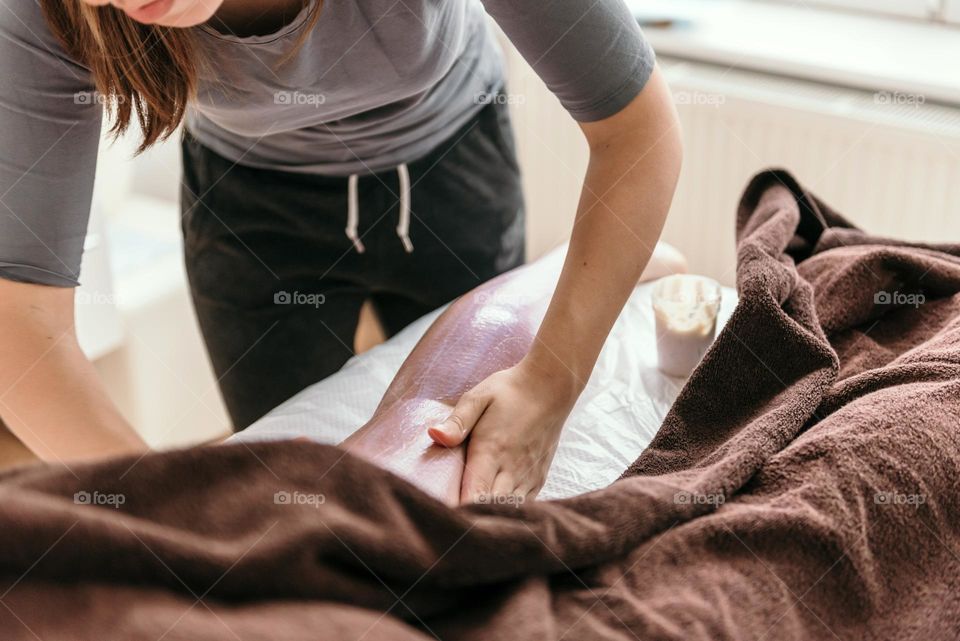 Masseuse doing legs massage with skin peeling on young woman