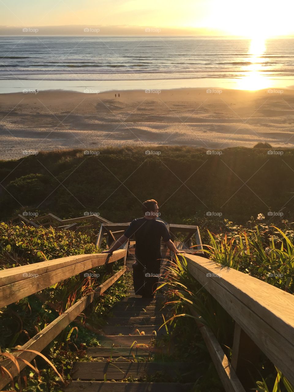Man walking on staircase in front of beach