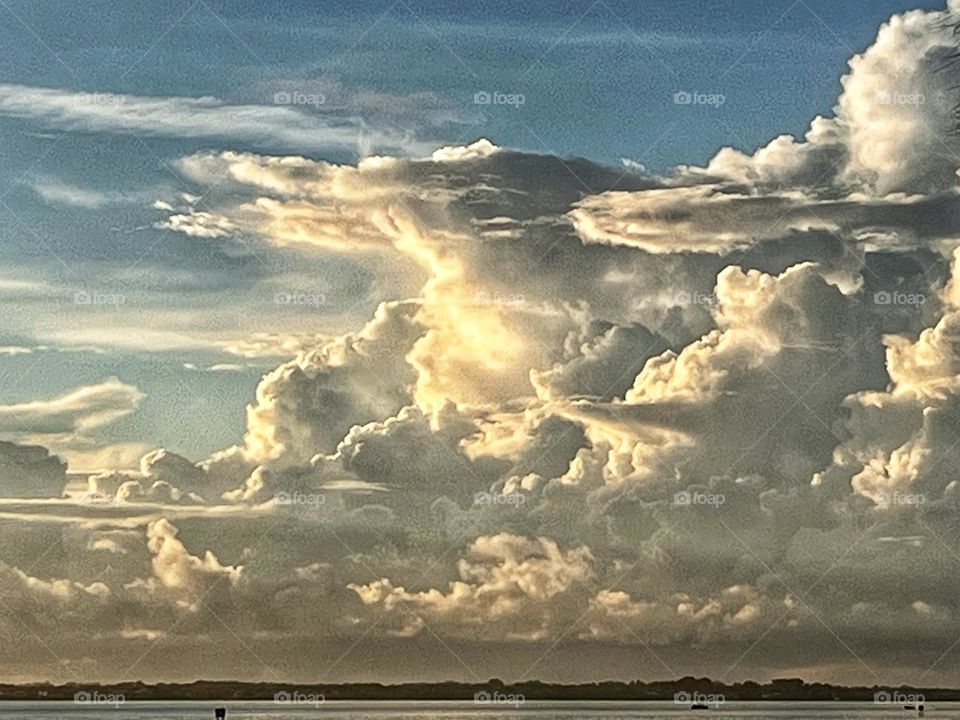 Large white cloud formations at sunrise over the river