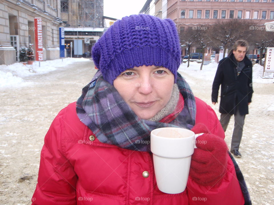 Hot chocolate at outdoor Christmas market europe. Rugged up in coat and hat. Cold. Woman in red coat enjoying hot chocolate.