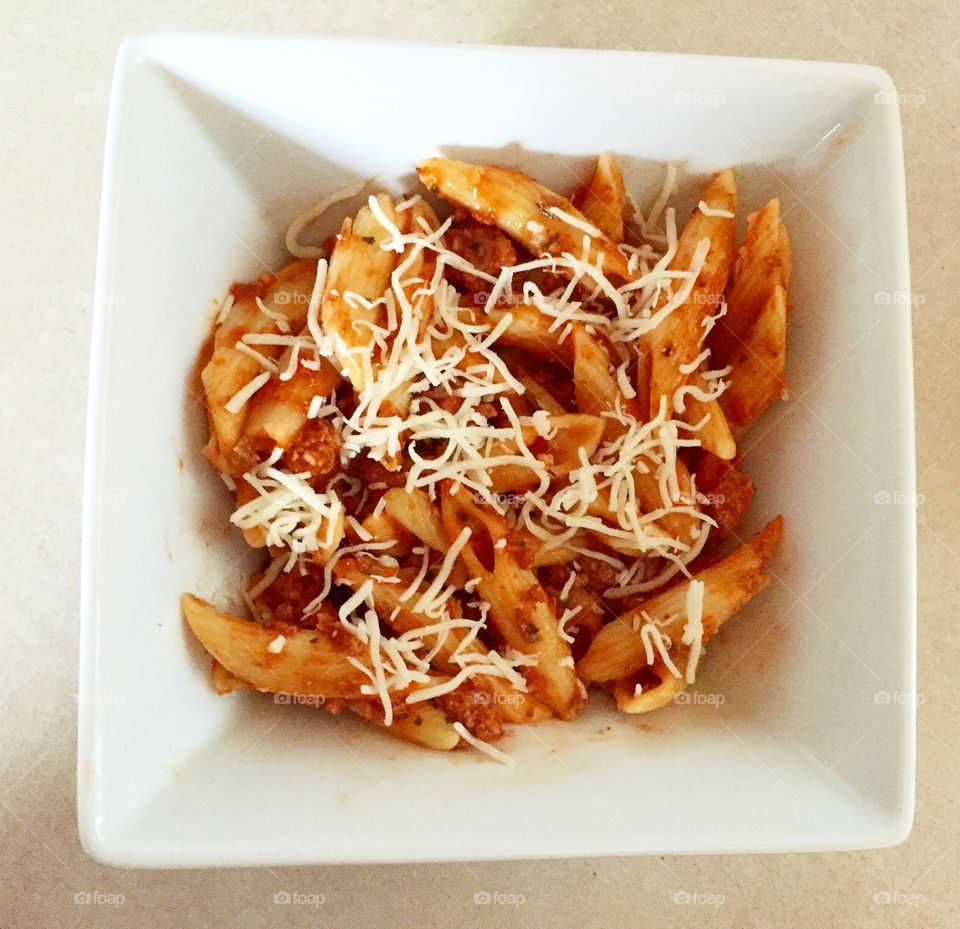 Pasta garnished with cheese in bowl