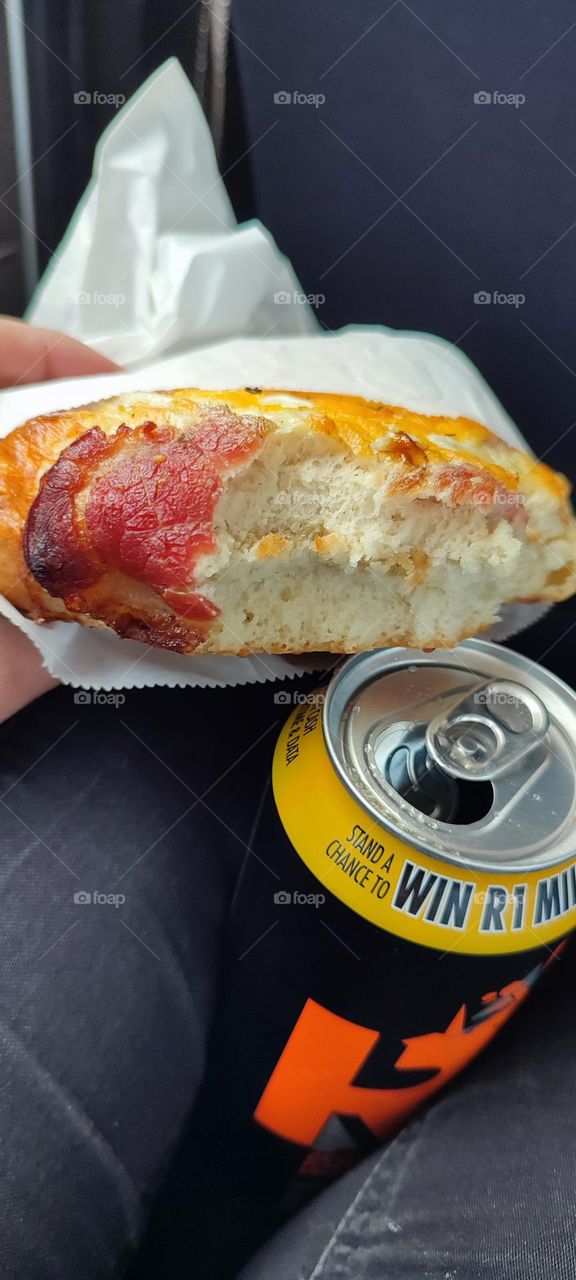 Eating a Bacon & egg bun, drinking Engergy drink in the back of a car.