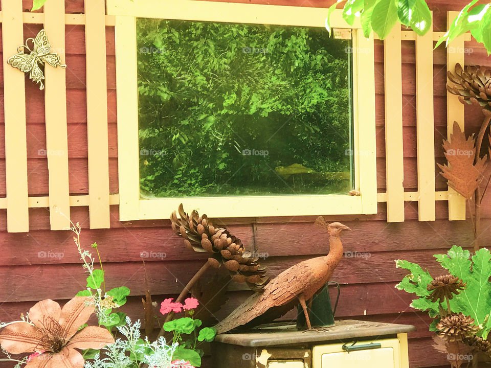 Framing & colour balance: The bright green reflected tree is framed beautifully by the yellow window frame & the rust red wall and metal art & balanced again by the re-used yellow stove that matches the window frame.