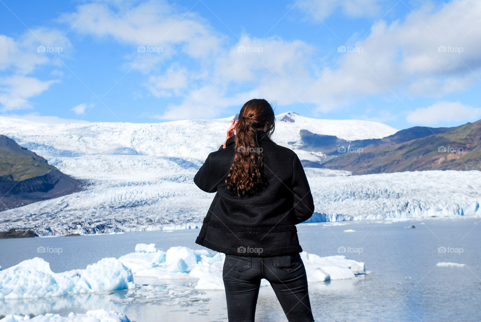 Girl stands in front of a glacier and glacial lake
