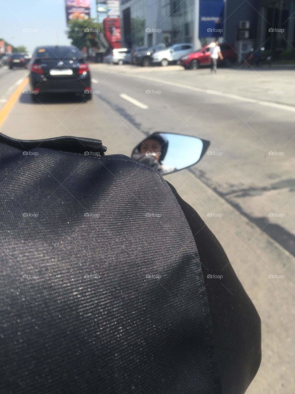 Riding a motorcycle in a busy highway under the sun.