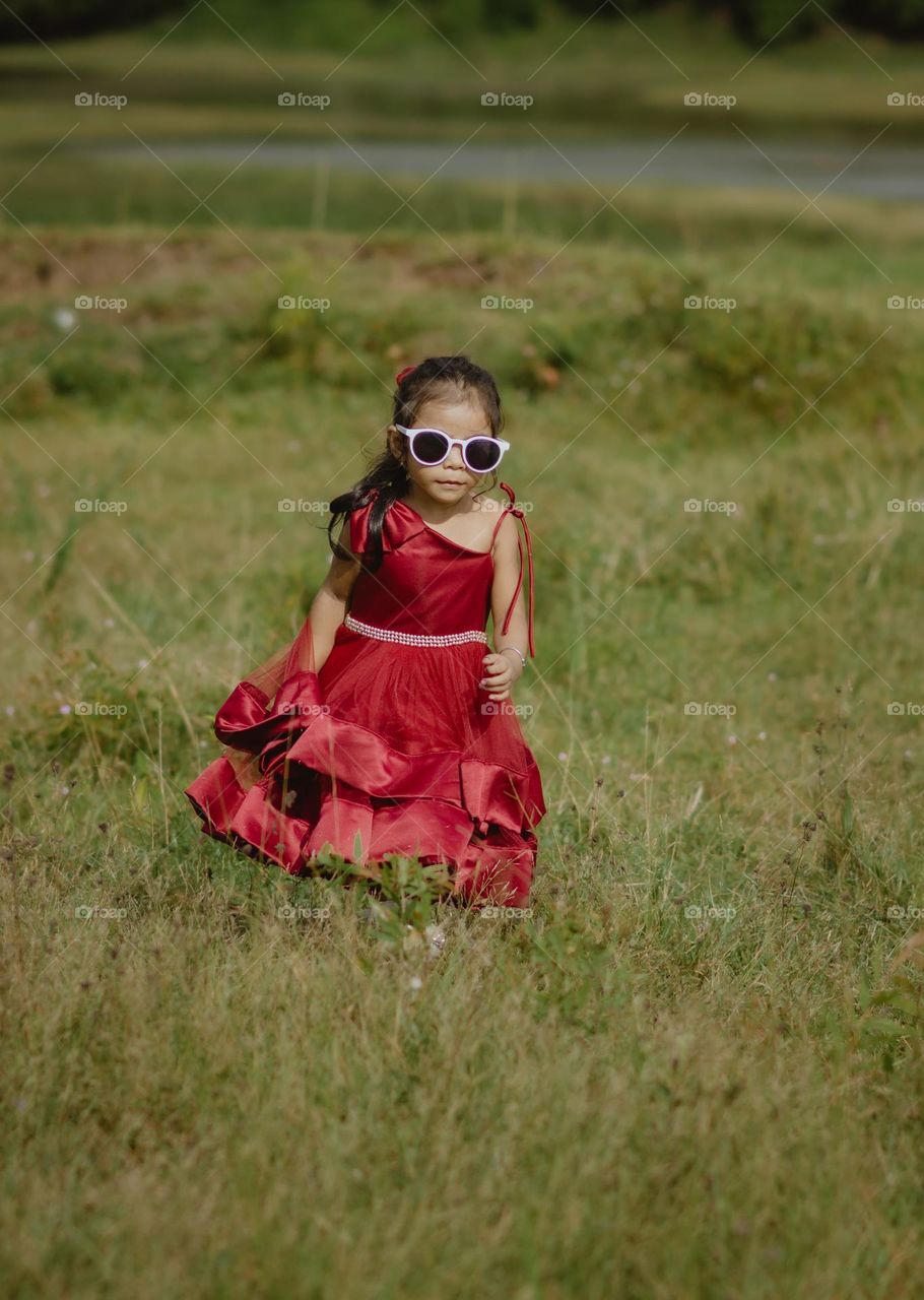 kid with sunglasses playing in green park