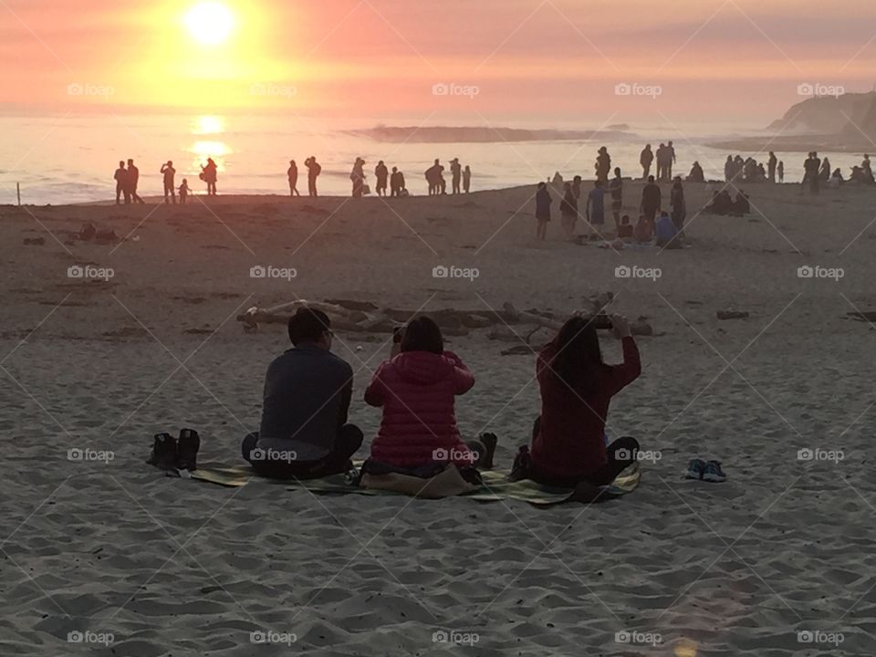 Tourists watching sunset on a beach