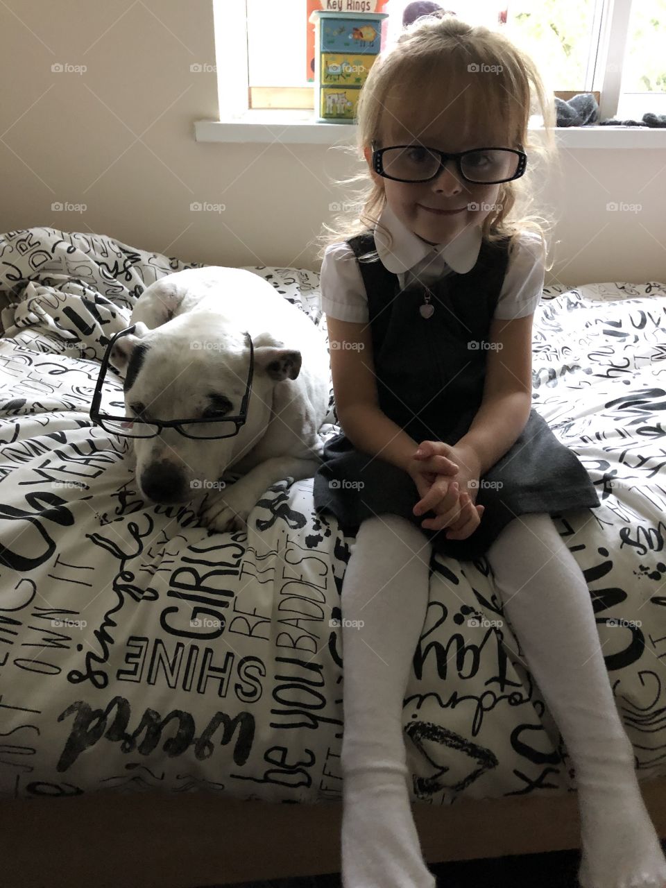 Little girl put glasses on the dog to play teacher’s 