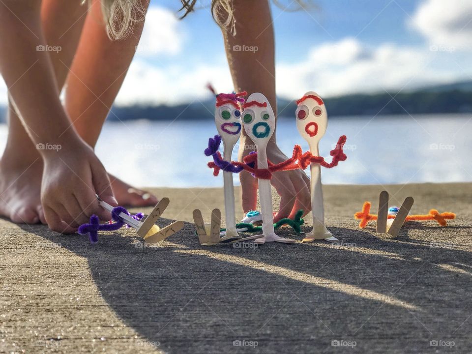 Bright colorful Spoon character modeled after forky craft with spoon friends made by young children on hot sunny day at lake house 