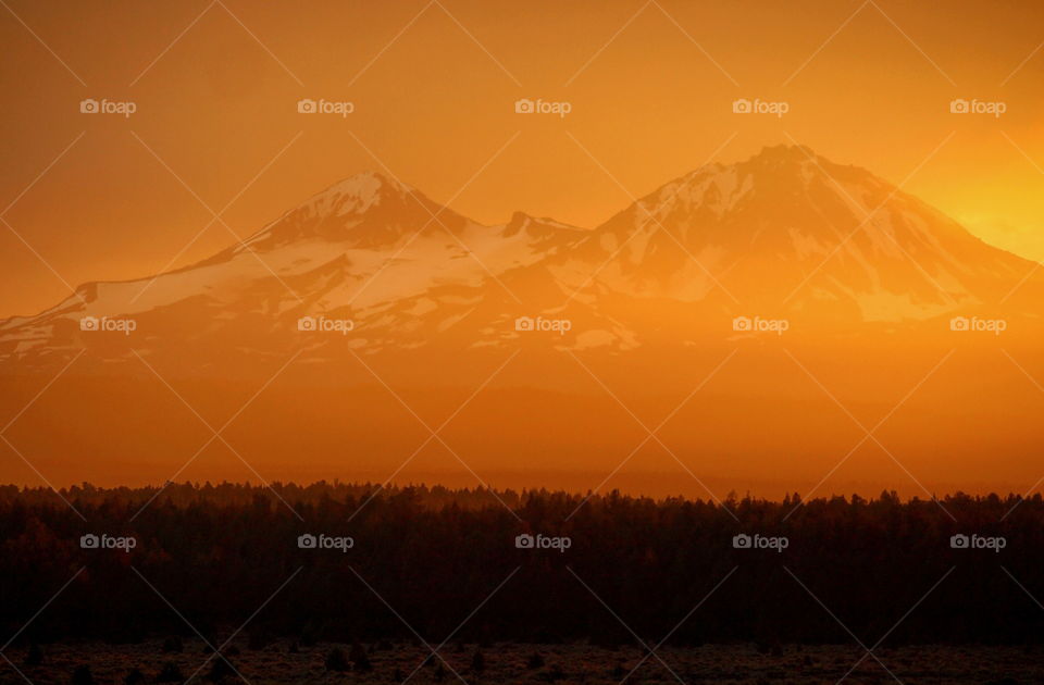 A very rare orange atmospheric glow over the Three Sisters in the Cascade Mountain Range in Central Oregon near sunset after a heavy rainstorm.