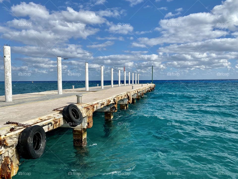 A dock sticking out into beautiful turquoise colored water 