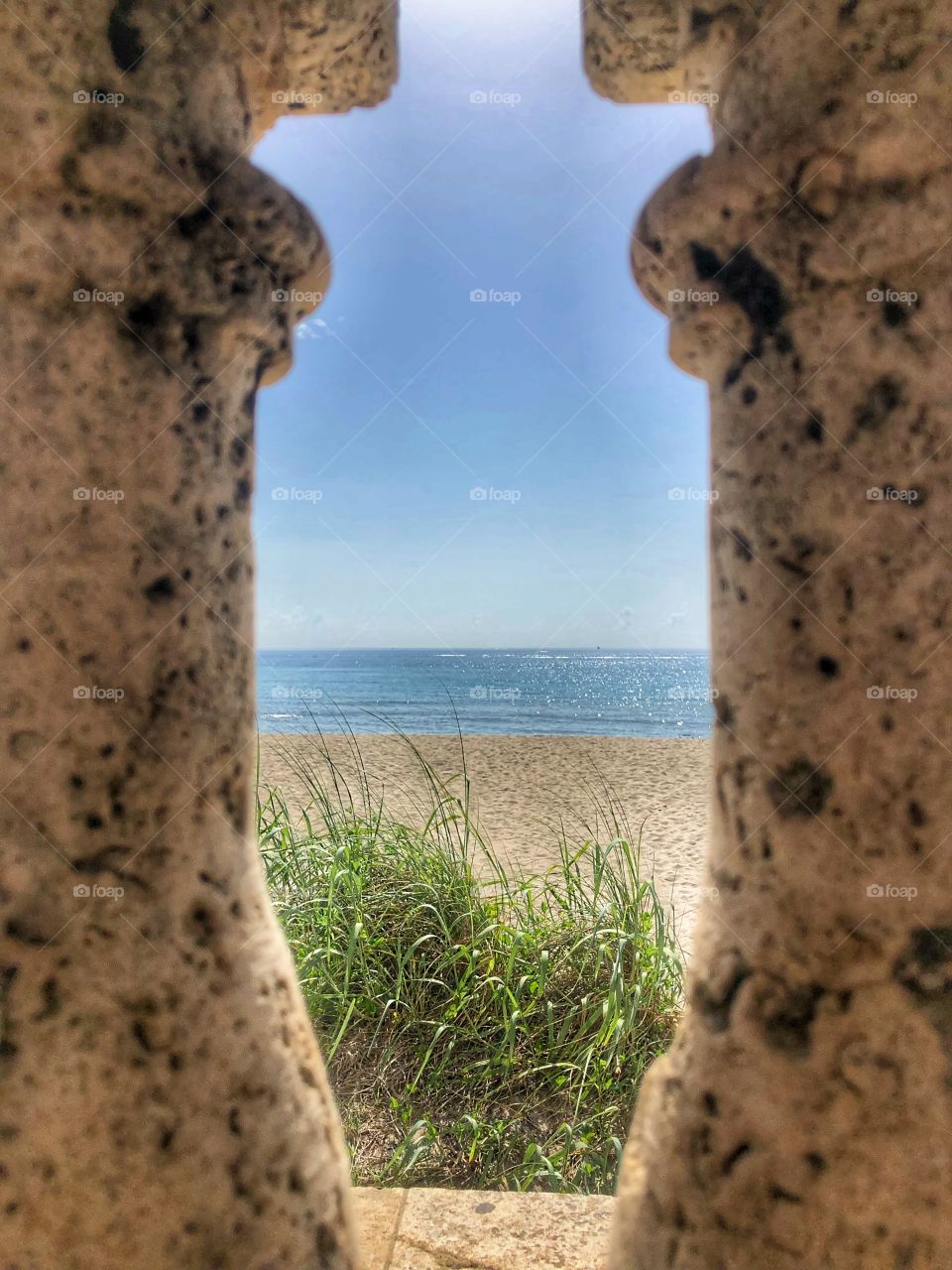 A peek at the beech through stone pillars at Palm Beach Florida clock tower 