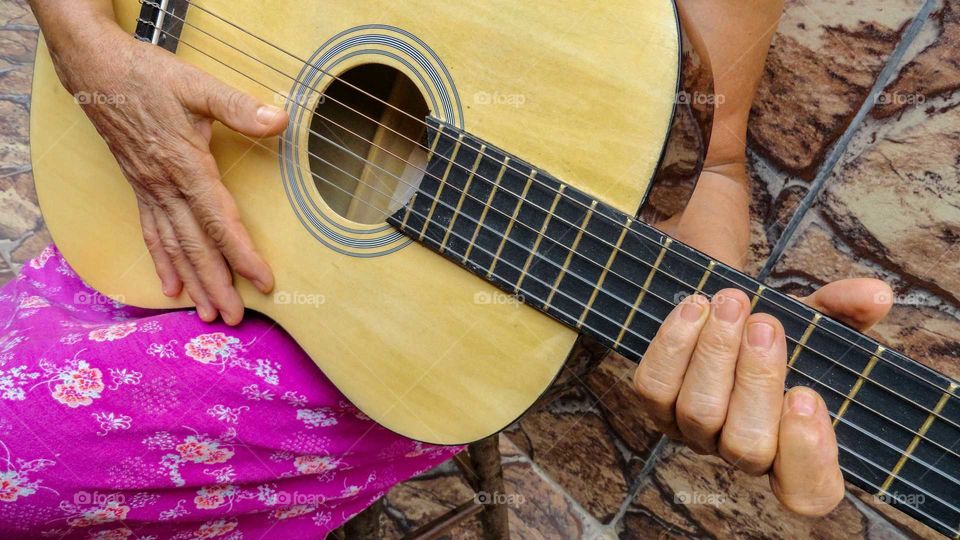 See someone old learn something new. Elderly woman learning to play guitar.