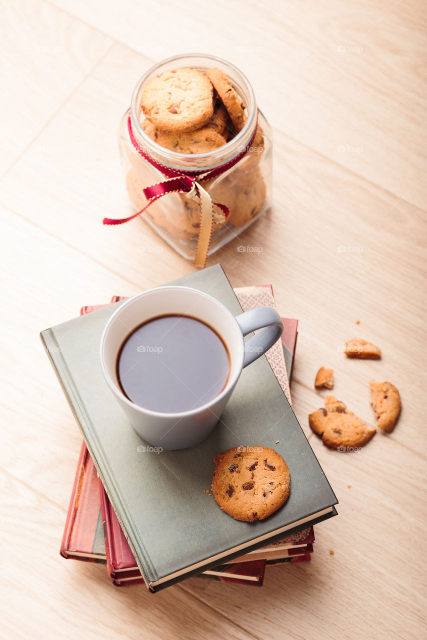 A few books with cup of coffee and cookies on wooden floor. Time for relax. Spending leisure time on reading