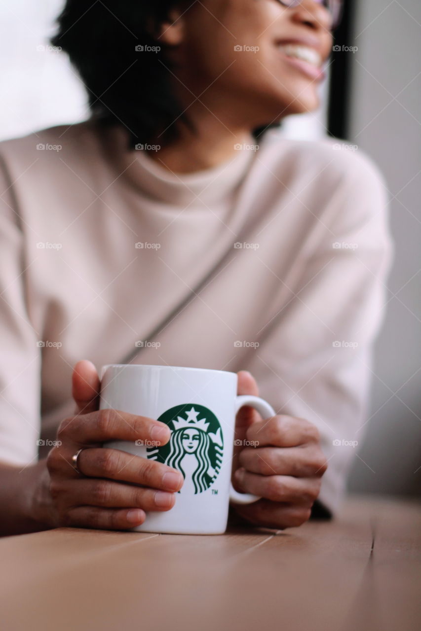 woman smiling while look out the window and holding the starbucks mug