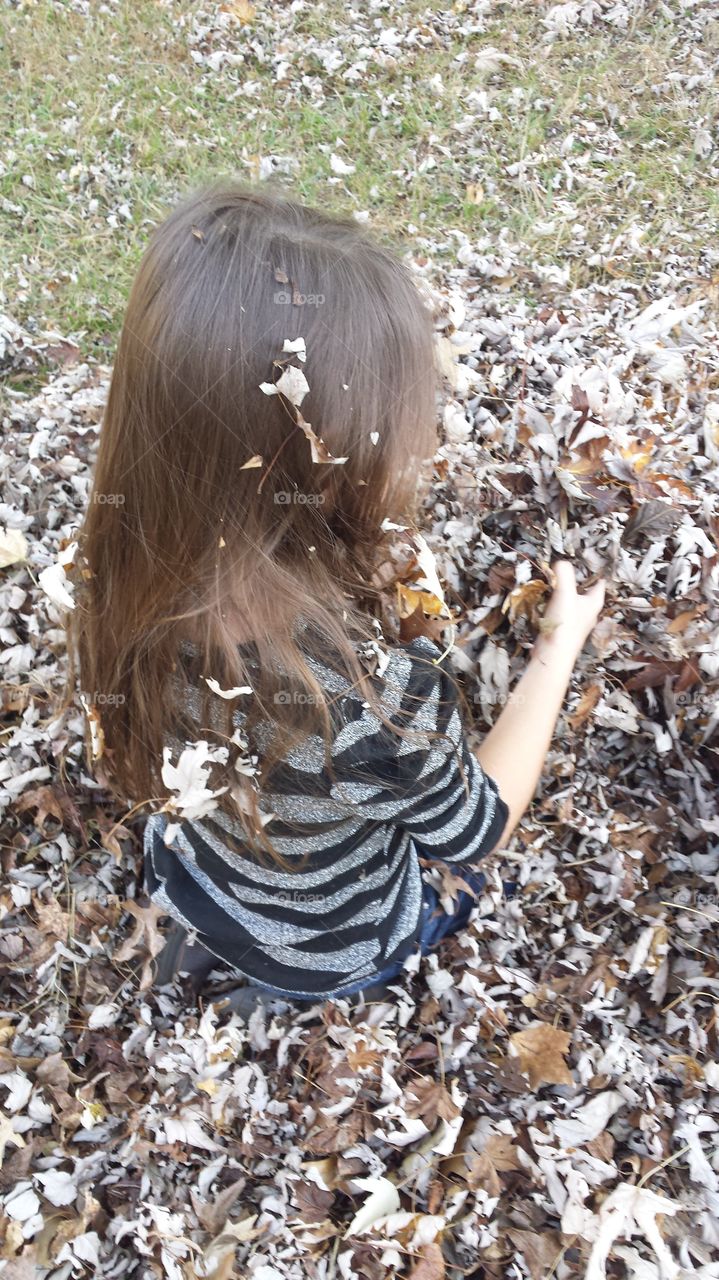 Young girl playing in fall leaves