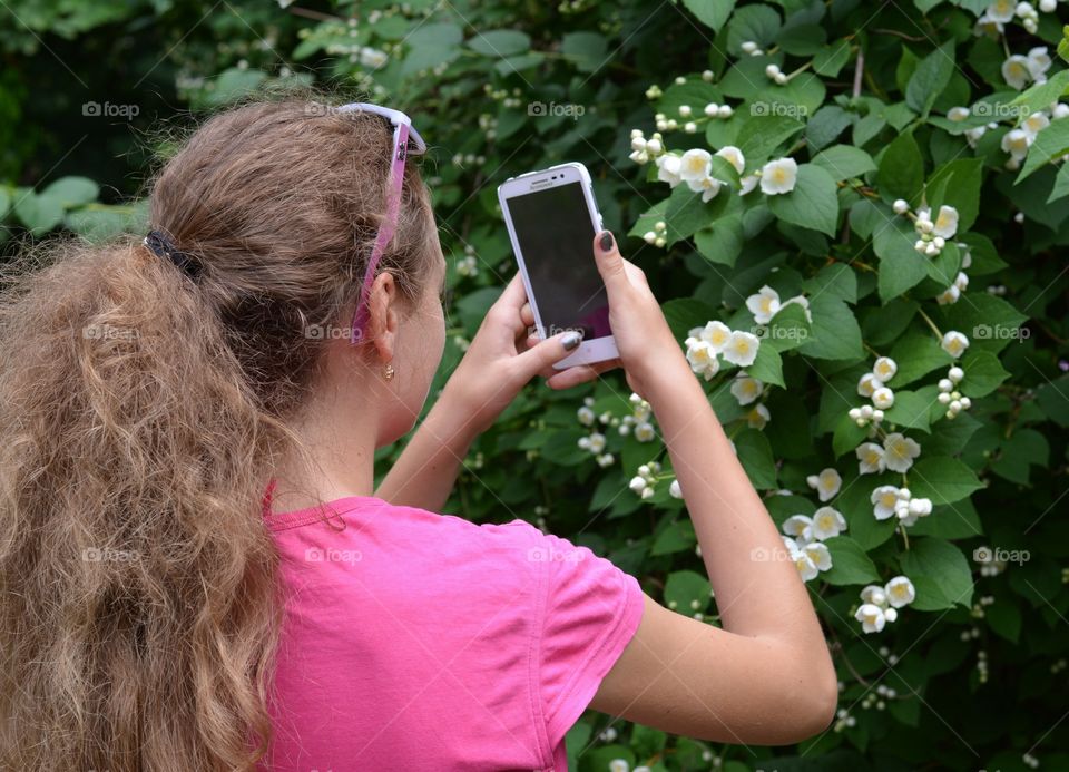 smartphone in the hands girl take pictures flowers in the summer park