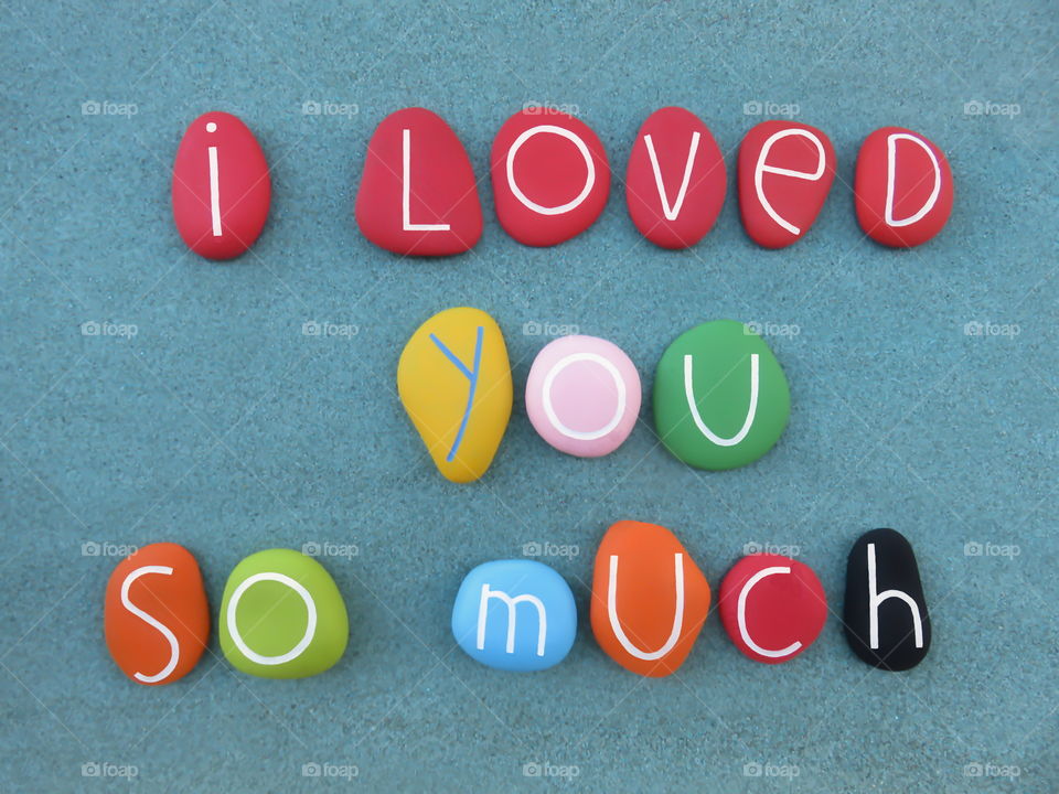 I loved you so much, creative message composed with multi colored stones over green sand
