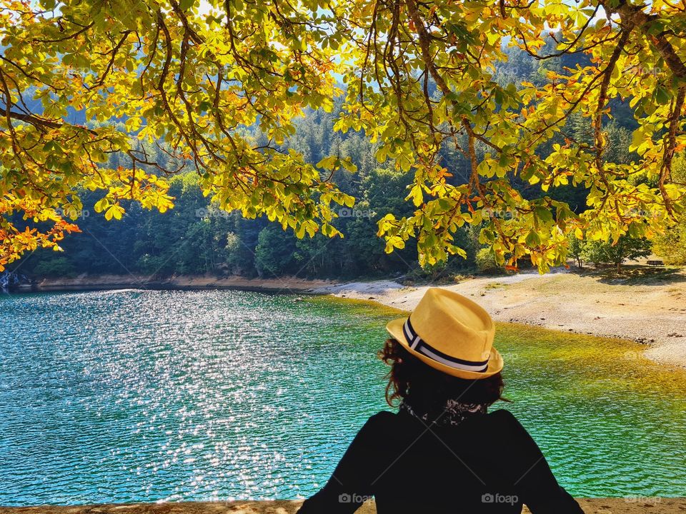woman from behind with hat looks at the lake