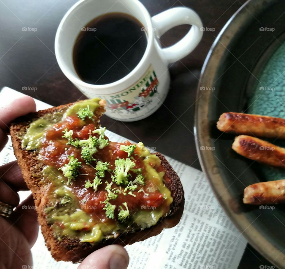 holding toast guacamole salsa sausages coffee newspaper plate table breakfast
