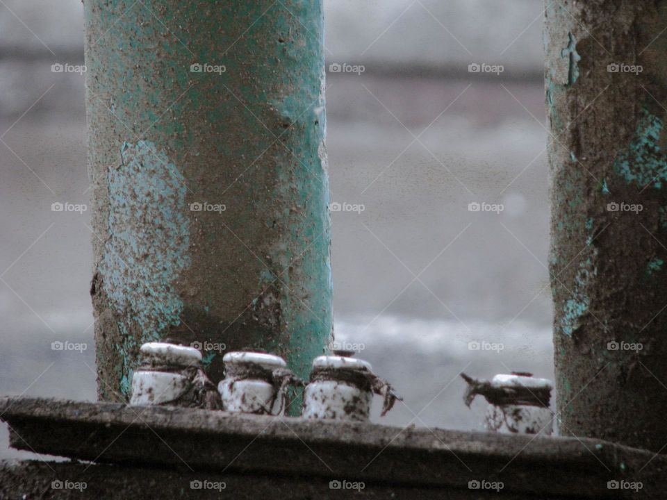 Close-up view of two iron posts attached to a concrete surface with bolts and nuts