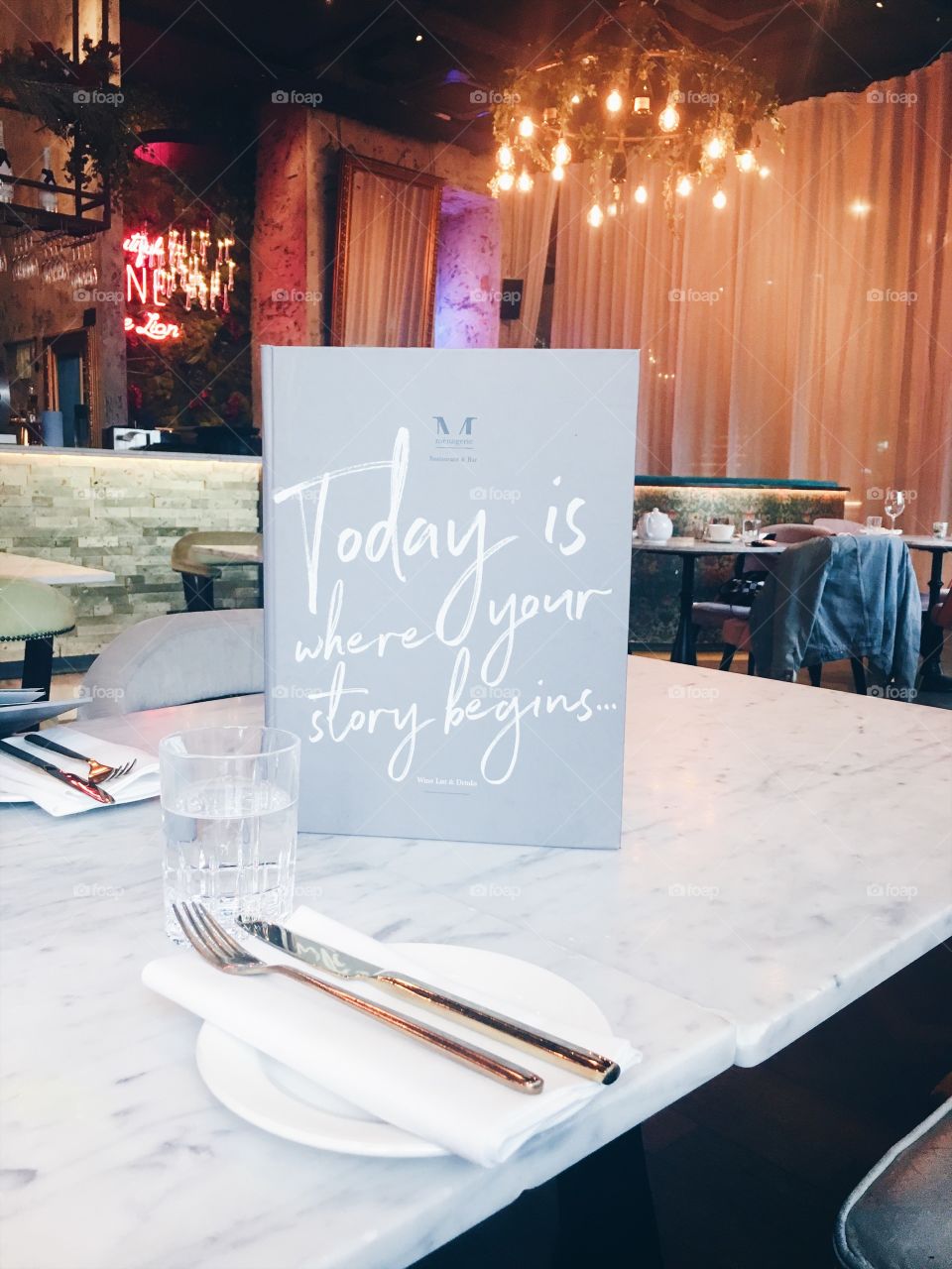 “Today is where your story begins” Food menu placed on marble table with gold cutlery in fashionable restaurant bar