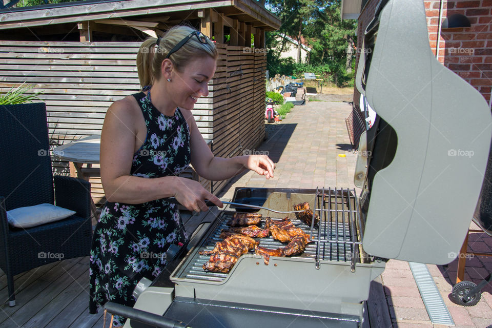 Woman working the barbecue in the summer in Höllviken in Sweden.