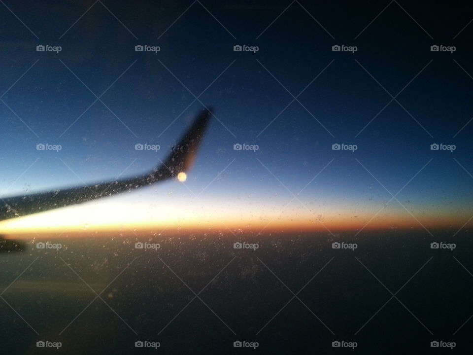 An airplane wing on sunrise, through a frosted glass