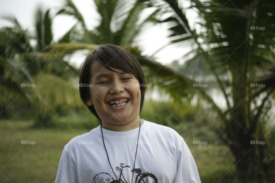 Real lifestyle portait young Asian boy lifestyle genuine smile on an nature setting outdoor