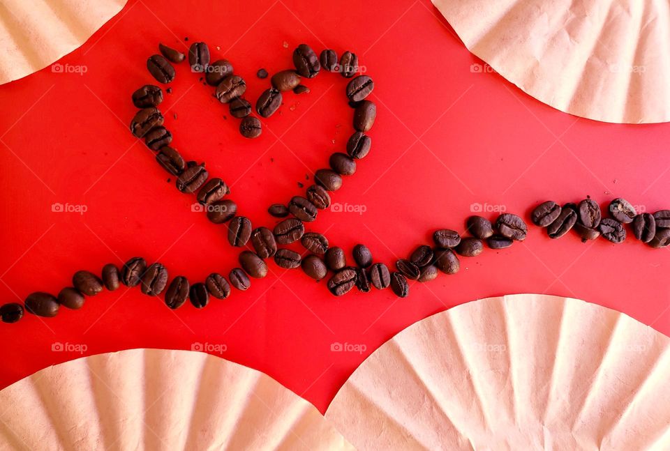 Coffee beans in a heart design on a red background surround by partial choice filters.