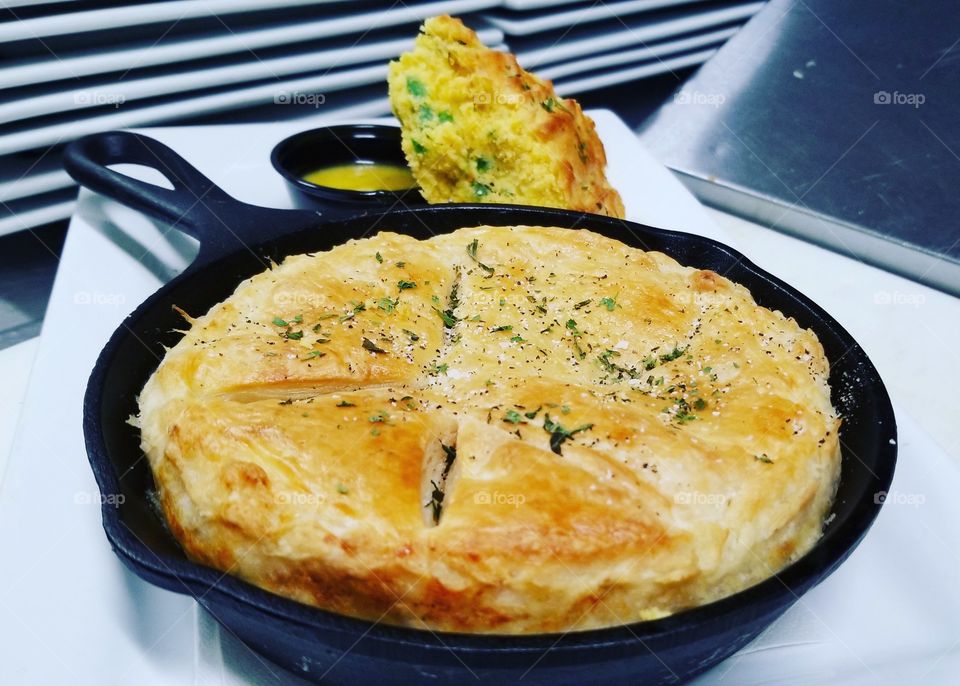 housemade skillet pot pie at obriens in Wesley Chapel Fl, roasted chicken, green beans, carrots, potatoes and onions I'm savory gravy topped with a puff pastry crust served with jalapeno corn bread and drawn honey butter
