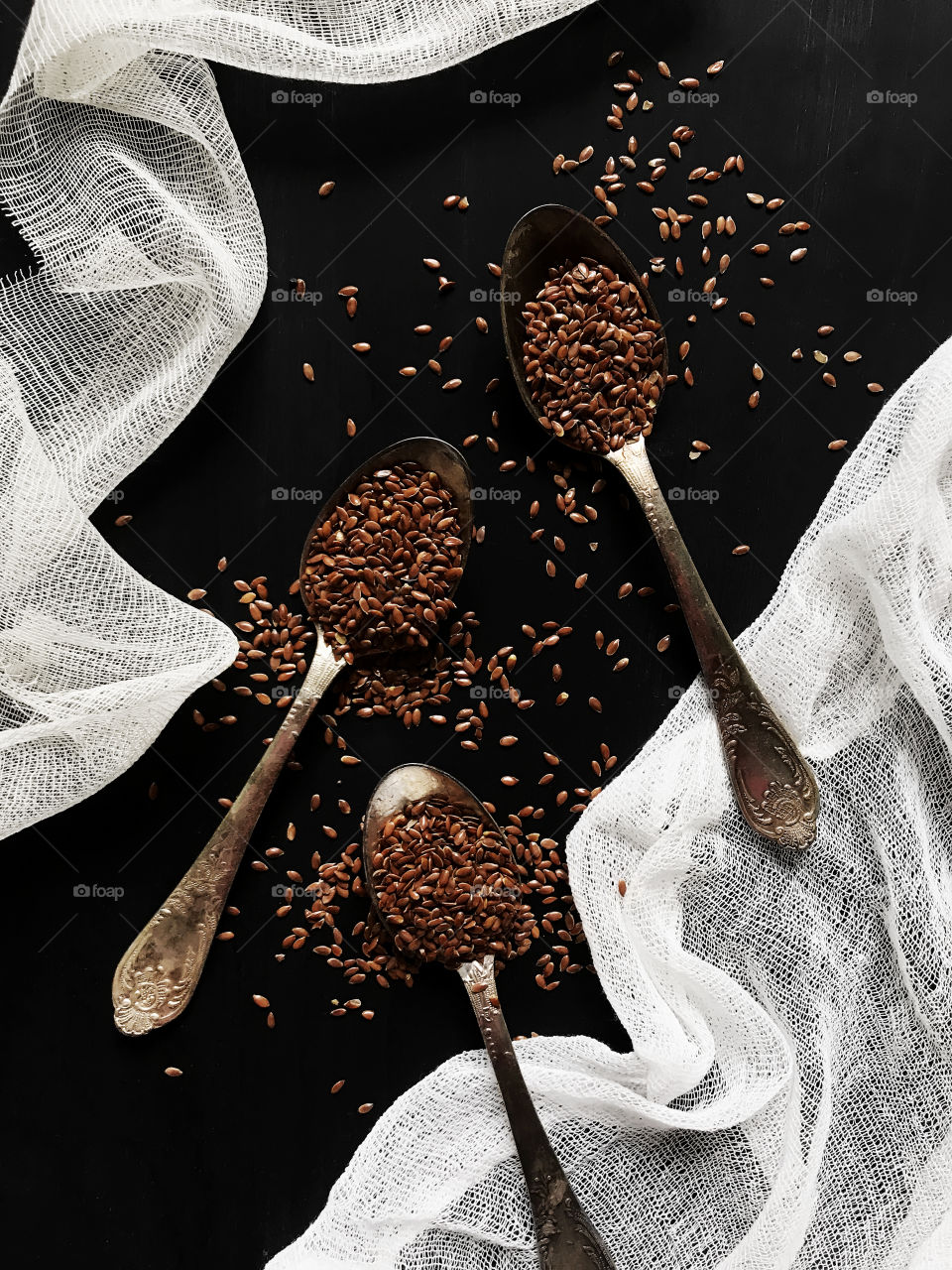 Three spoons with flex seeds on black background 