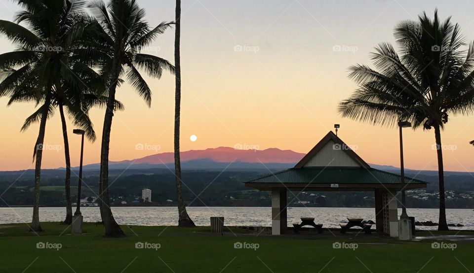 Moon receding as the sun illuminates the volcano