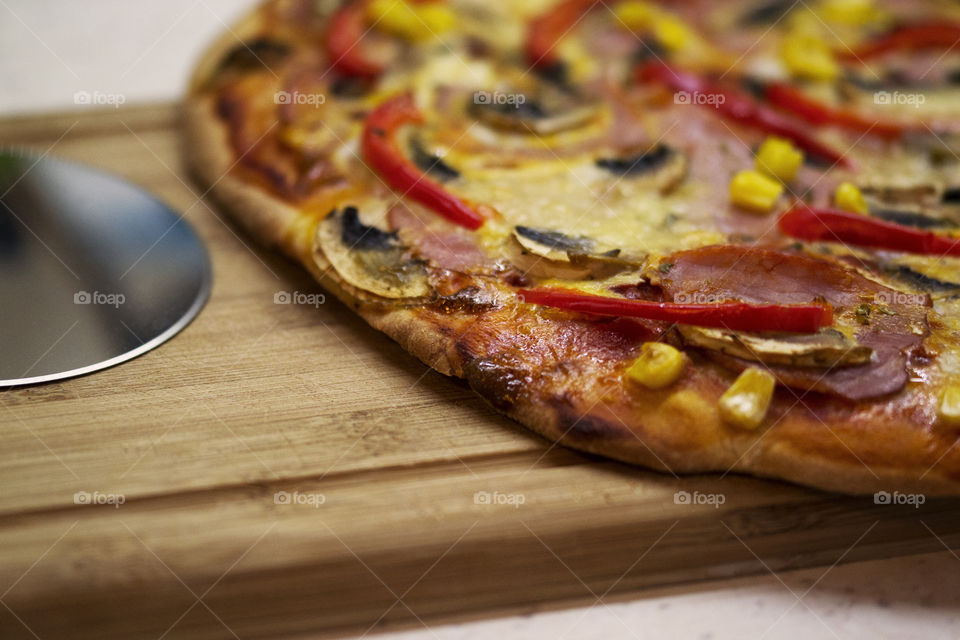 Close-up of a home made pizza on the kitchen counter with a pizza slicer