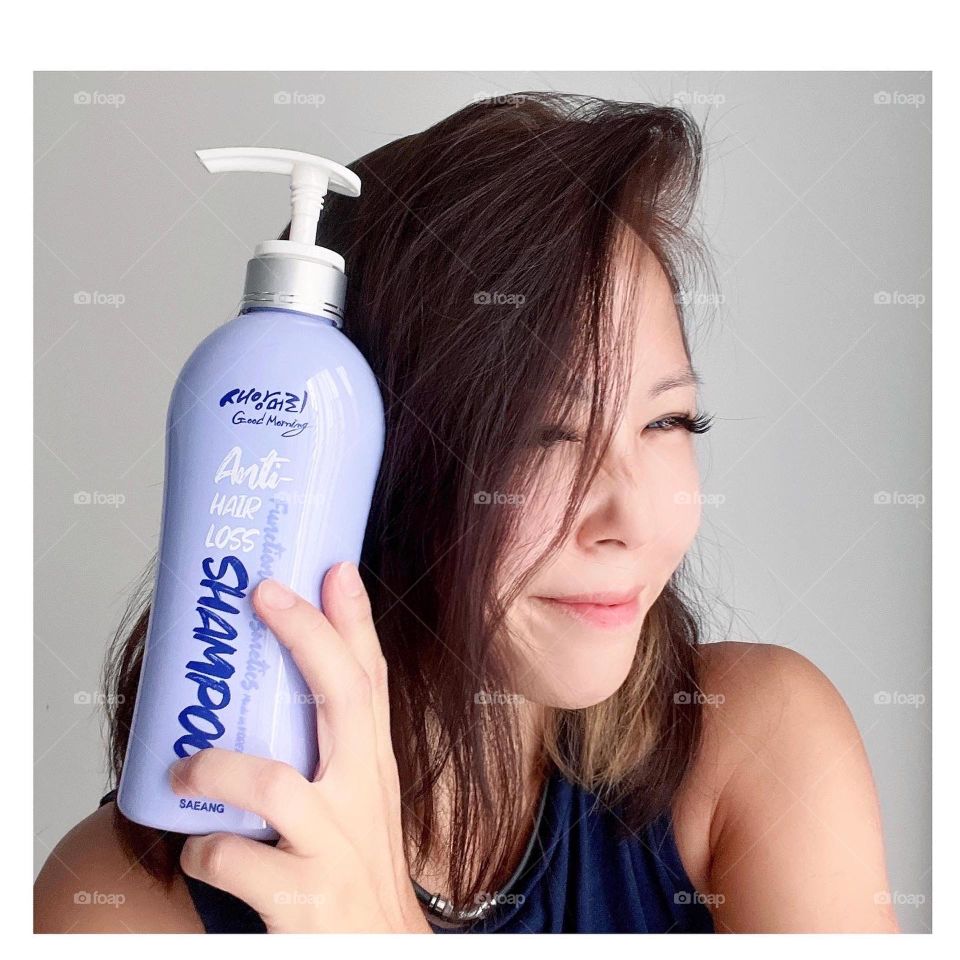 Asian woman holding Anti hair loss shampoo made in Korea cute packaging 