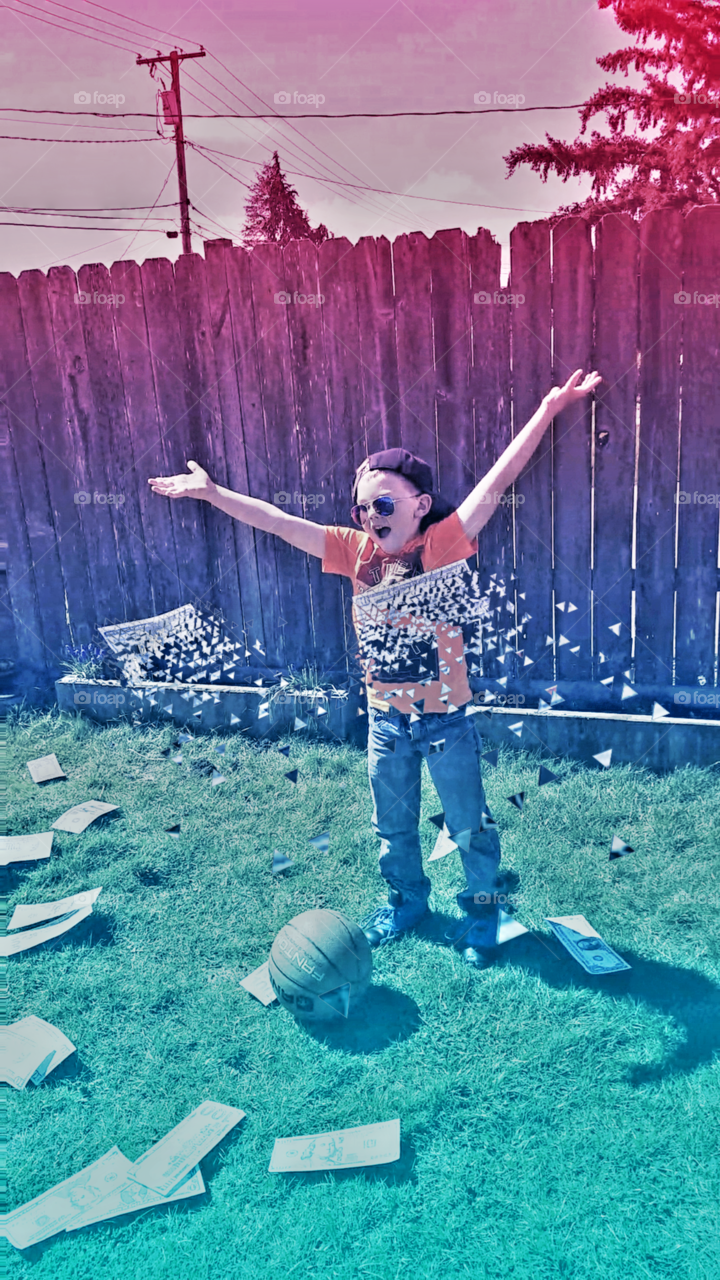 Abstract image of boy with arms up, as money disintegrates mid-air, in front of him.