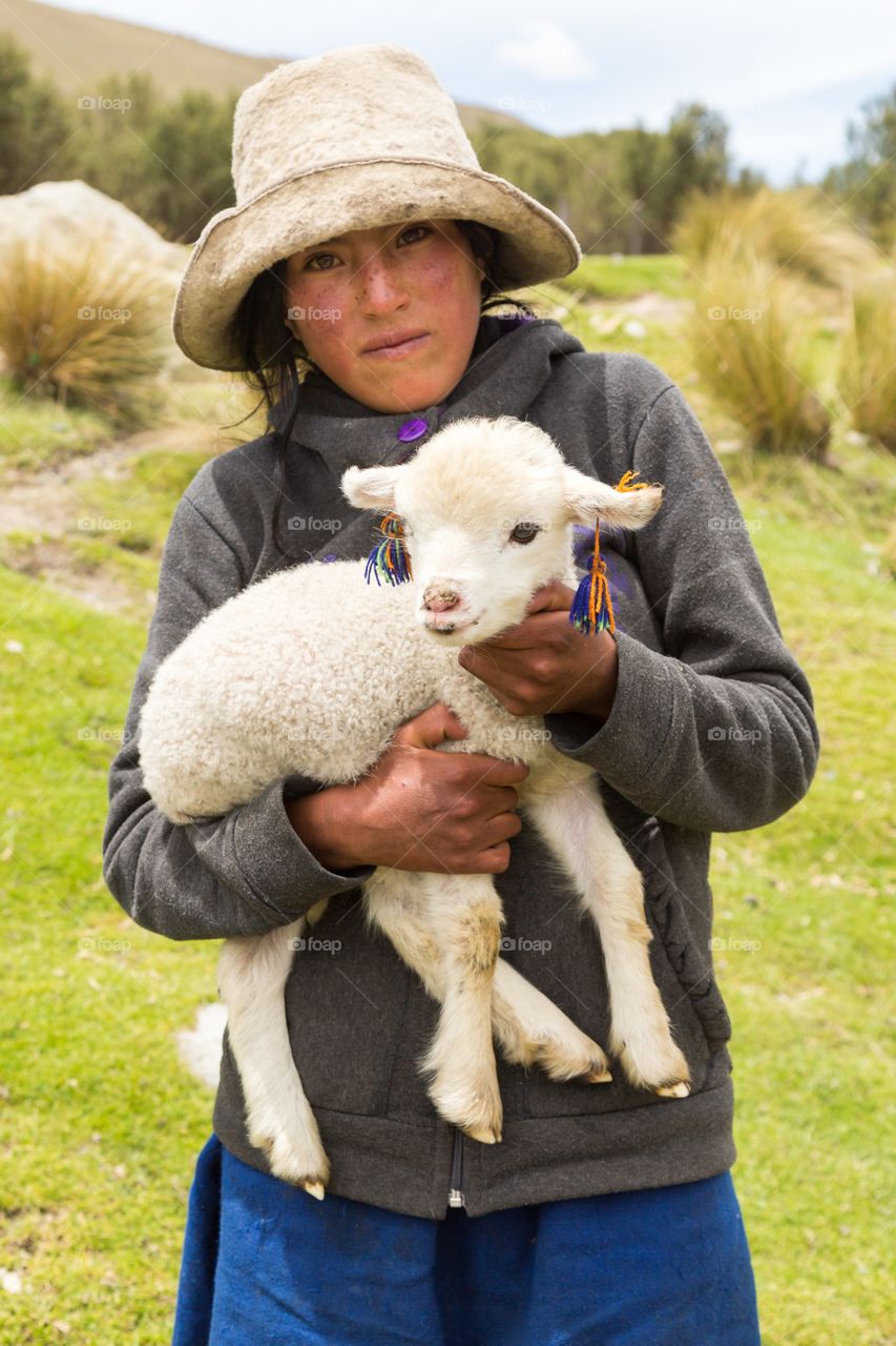 Peruvian girl and lamb posing. Peruvian girl posing for my camera. White felt hat. Girl is carrying white lamb with colorful ear decoration