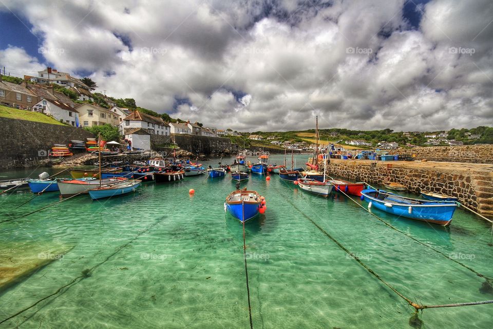 The harbour at Coverack in Cornwall on a beautiful sunny day. A typical Cornish harbour with fishing boats and emerald green sea.