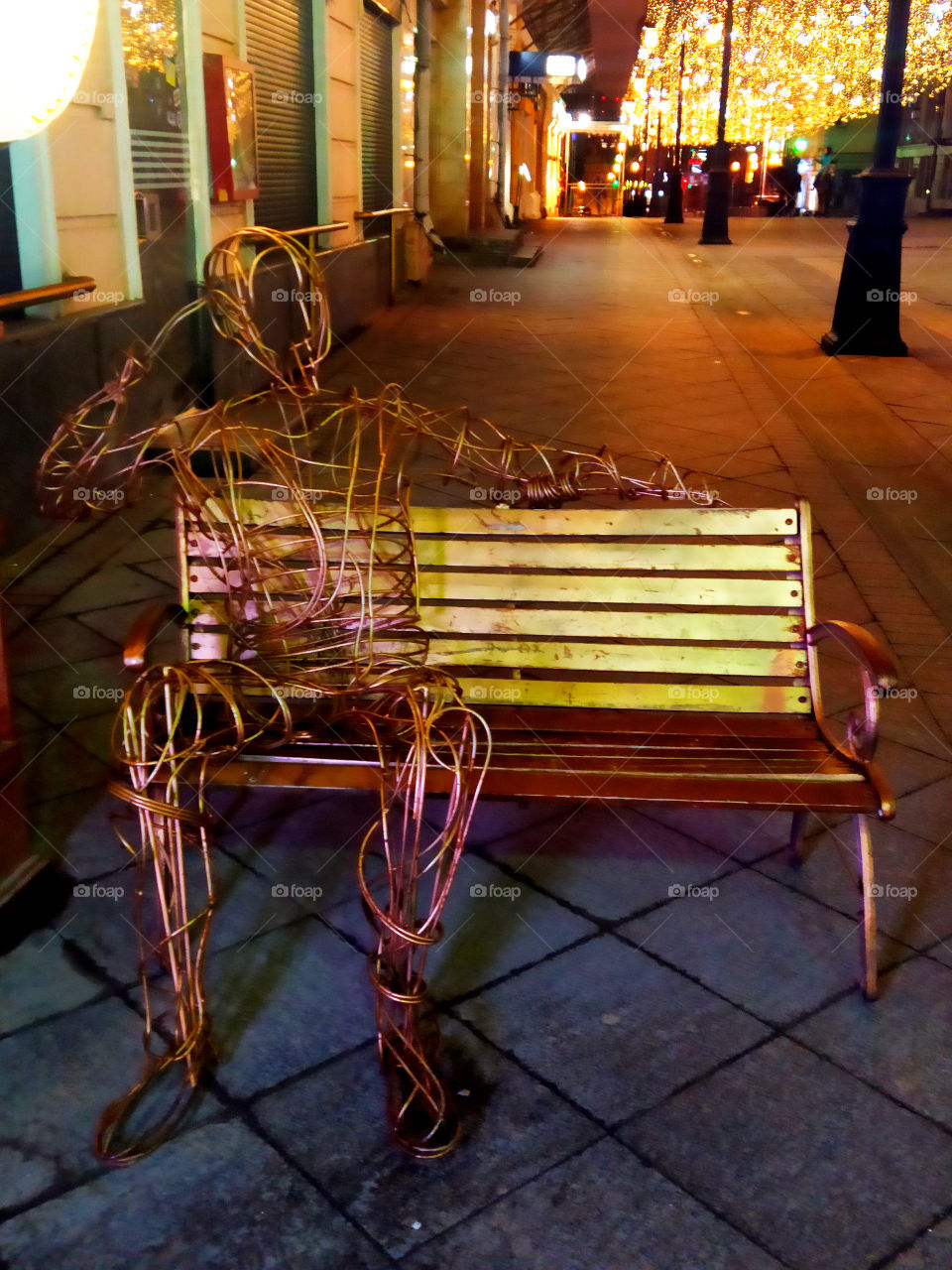 The man who is made of wire is resting on the bench