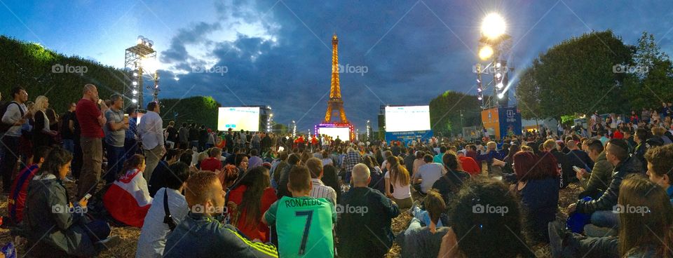 Sport brings people together.  UEFA EURO 2016 football action under the sunset and Eiffel Tower. 