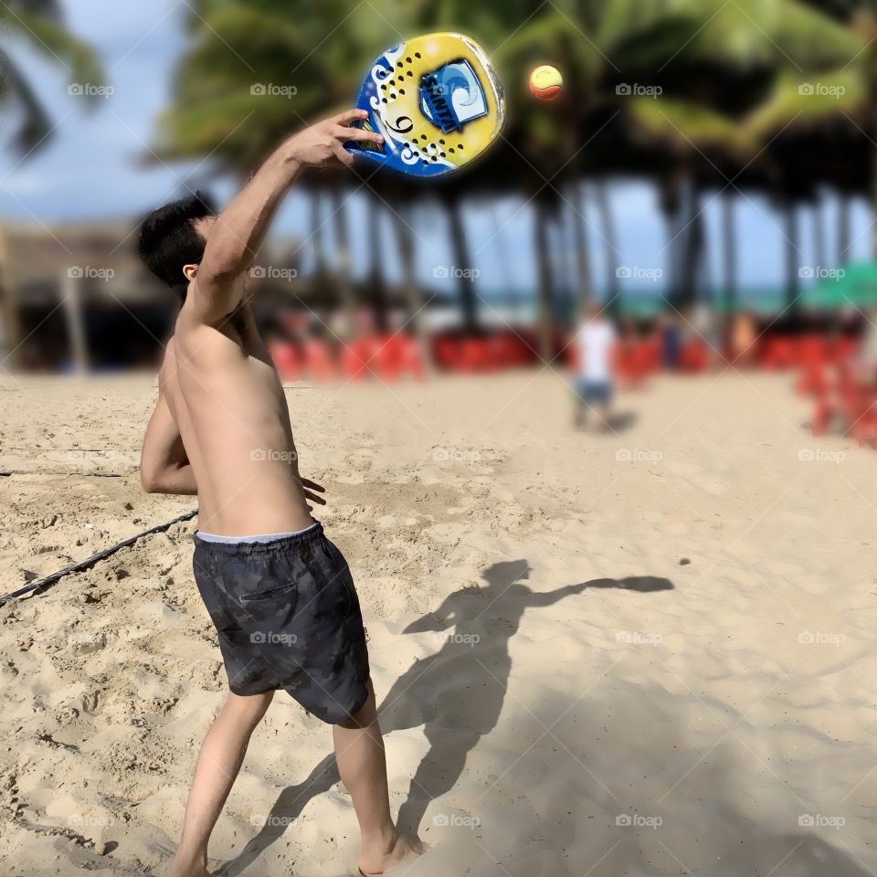 Little boy playing paddleball on the beach