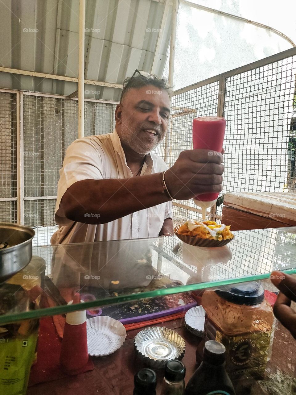 photo of a Sandwich shop owner, while preparing the order of their customer.
