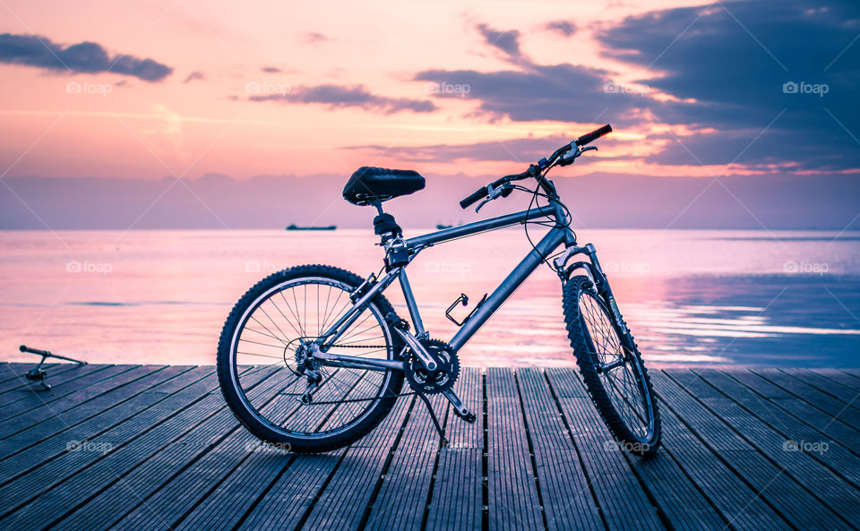 Silver And Black Hardtail Bicycle Parked On Wooden Boardwalk Under White And Blue Cloudy Sky During Dawn