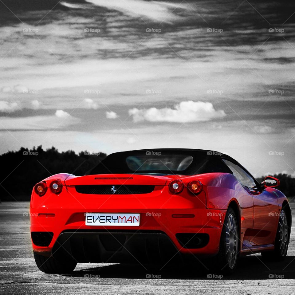 A scarlet Ferrari sits on a racetrack ready to speed off into the distance.