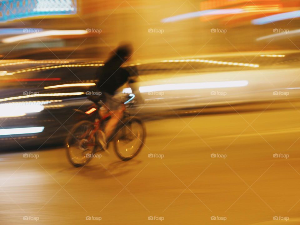 Young woman riding on bicycle around the city at night, long exposure 