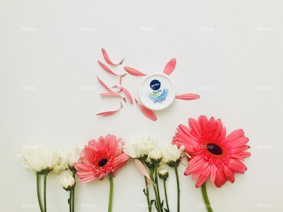 Nivea cream and beautiful colored flowers displayed on a white background 
