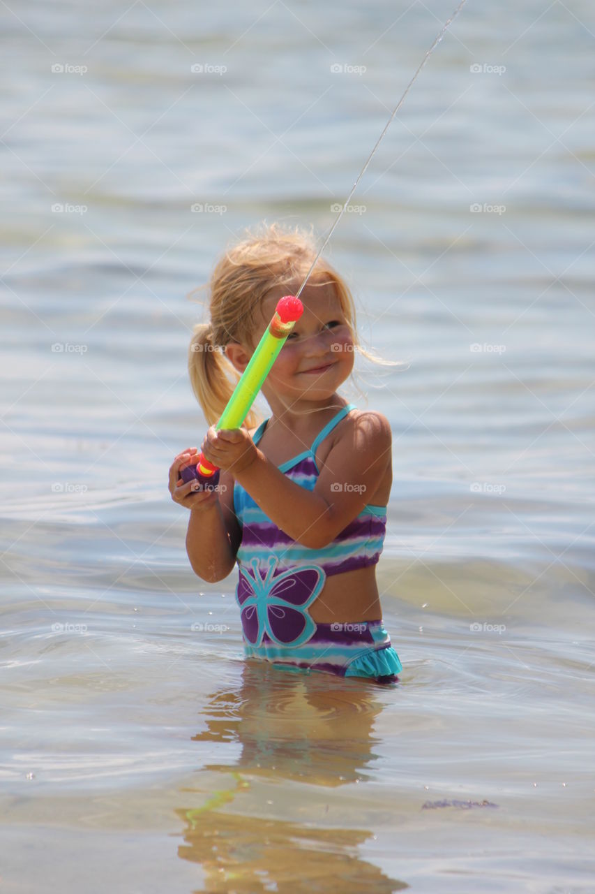 Little girl playing with water gun in the ocean