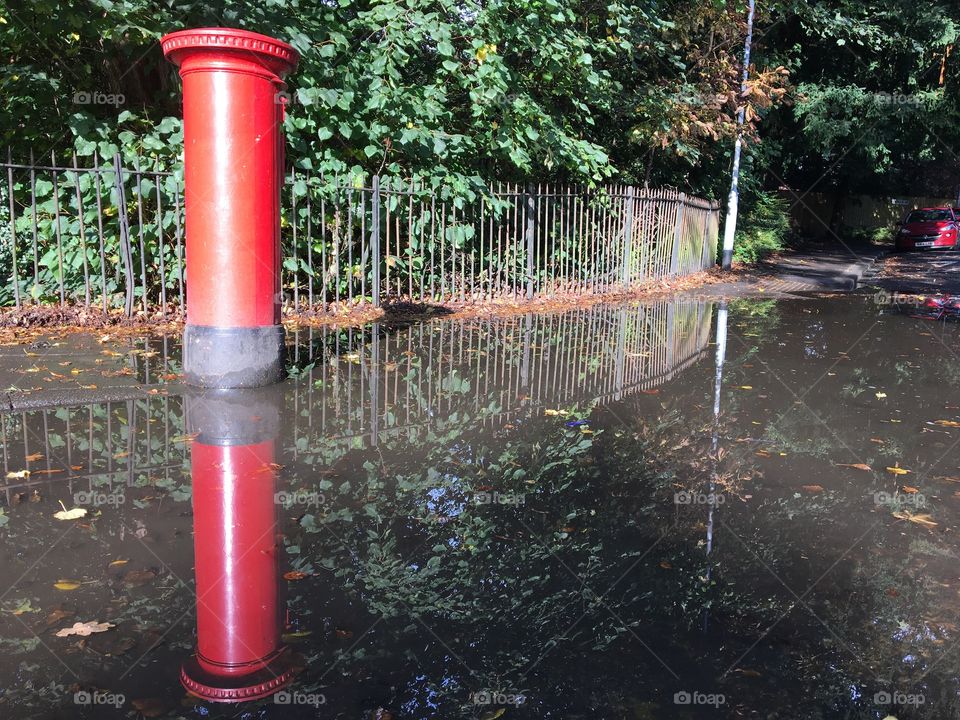 Flood ... Royal Mail Red Pillar Box reflection in a puddle after heavy rain 