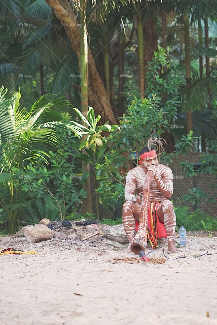 Gold coast, Australia - April 17, 2018 : A photo of Australia Aboriginal man is performing the musical instrument called Didgeridoo. Didgeridoo is 1 of the world oldest woodwind musical instruments.